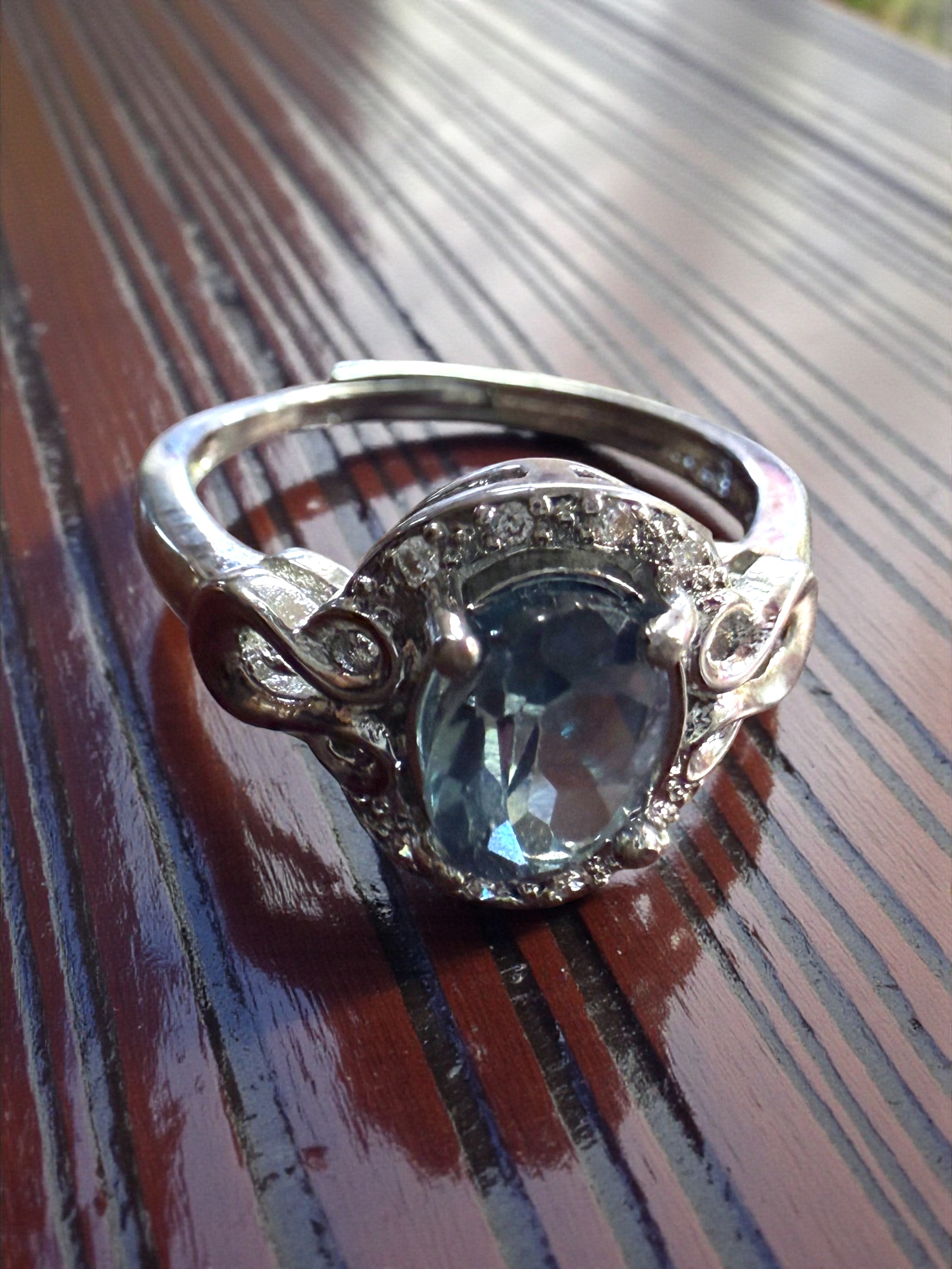 Silver ring with a blue gemstone on a wooden surface