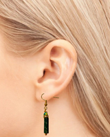 Green beaded earring worn by a person with blonde hair.